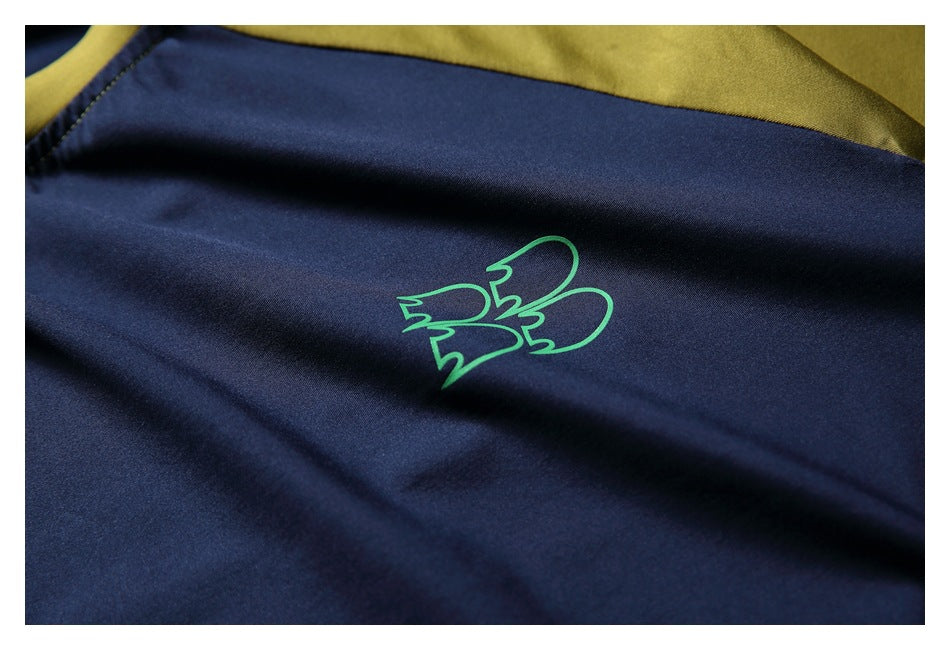 Close-up of a small green outlined graphic printed on the navy shirt, with mustard fabric above.