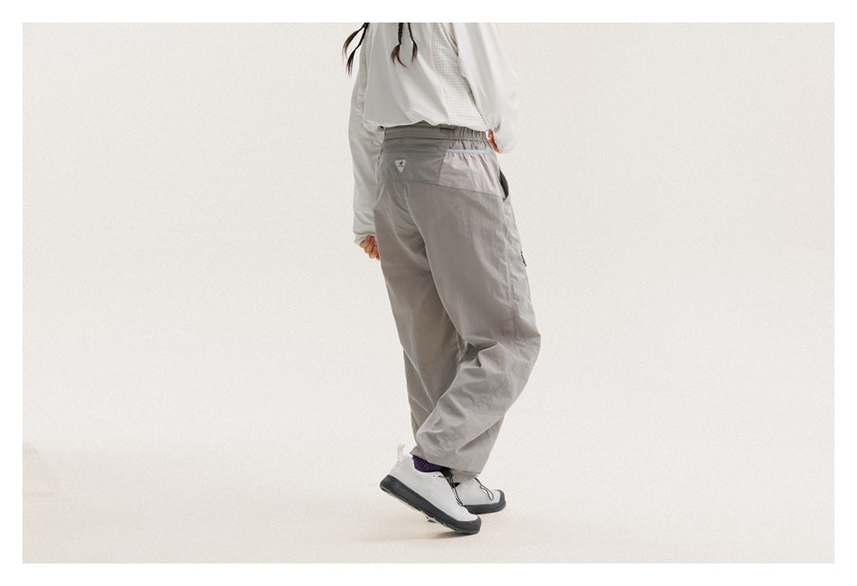 Cropped model showing the back and side of loose gray pants with an elastic waistband and rear pocket.