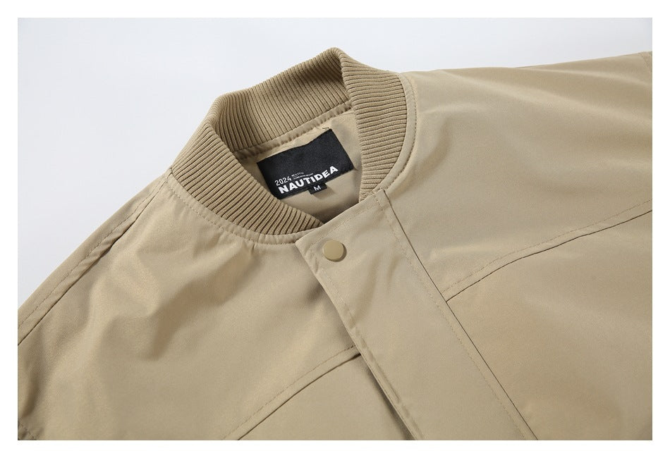 Close-up of a tan bomber jacket's ribbed collar, snap-front placket, stitching, and sewn-in neck label.