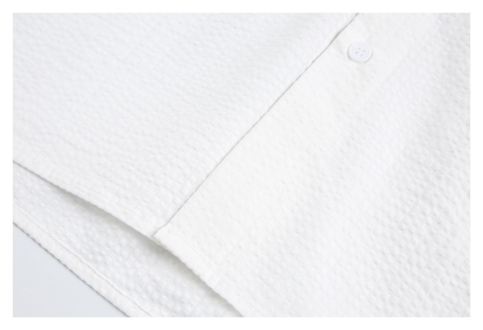 Close-up of the white shirt's button placket, hem stitching, and textured surface.