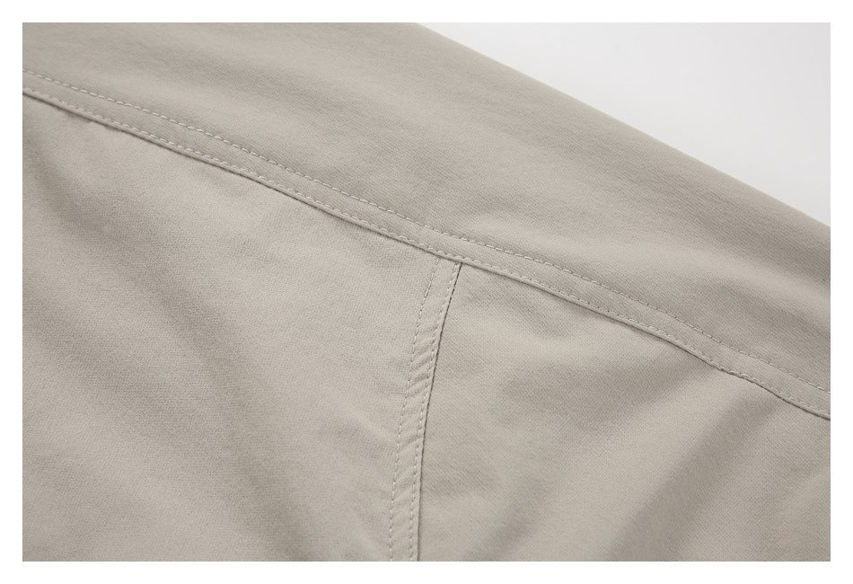 Close-up of a light taupe garment's stitched back seam and panel construction.