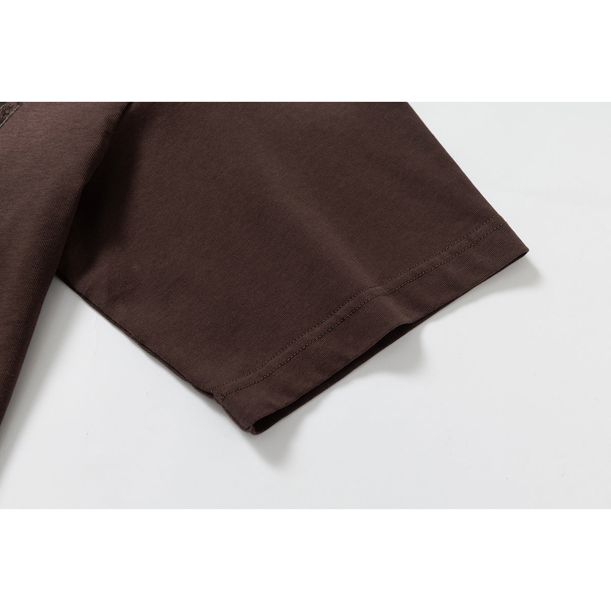 Close-up of the plain short sleeve and stitched hem of a dark brown T-shirt.
