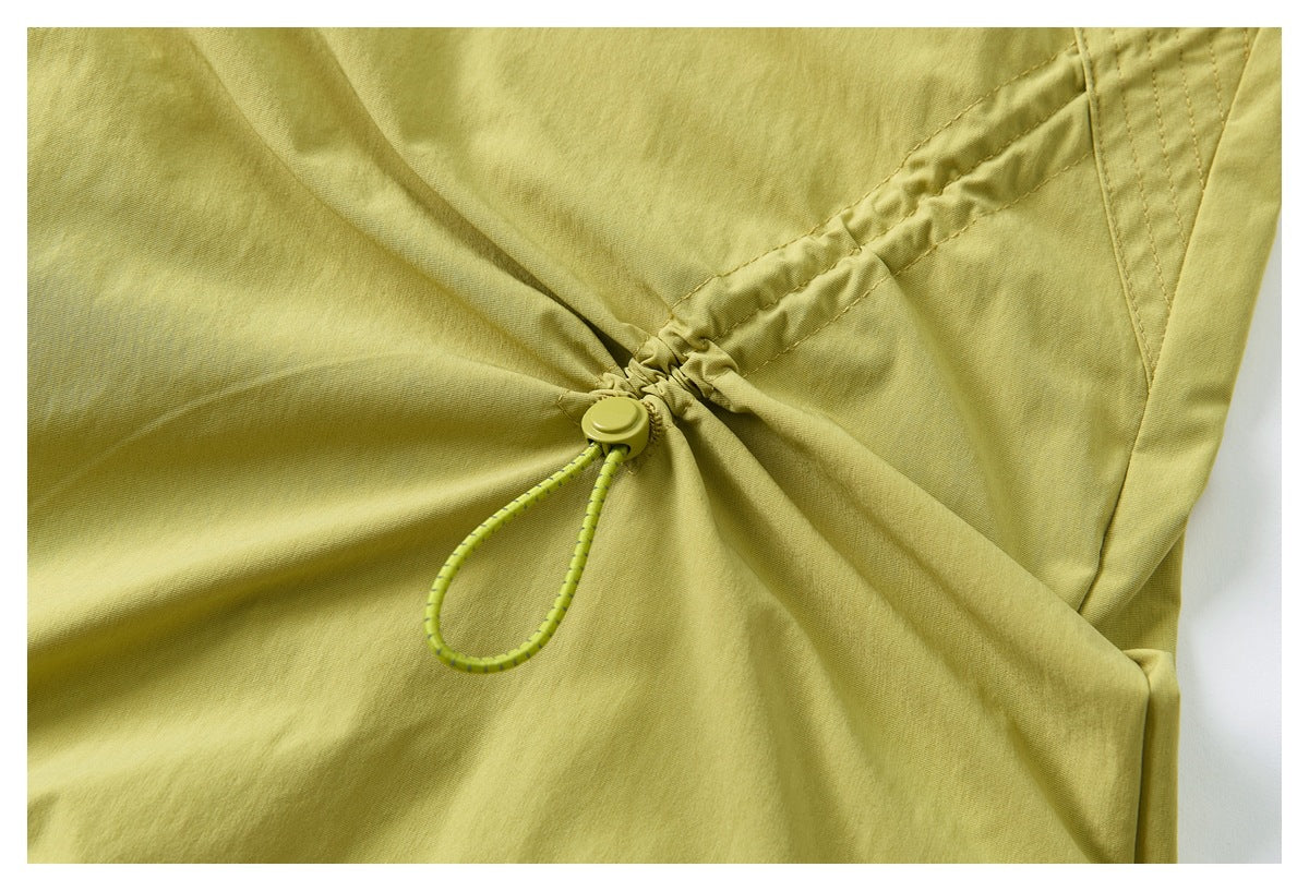 Close-up of yellow-green pants showing a gathered section with an elastic cord and toggle adjuster.