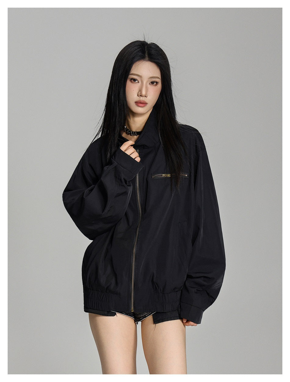 Model wearing a black oversized zip-front jacket with a stand collar, chest zip pocket and gathered hem.
