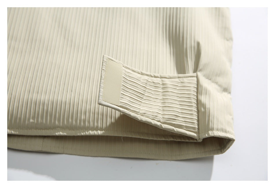 Close-up of an ivory vest's ribbed side tab and hook-and-loop fastening near the hem.