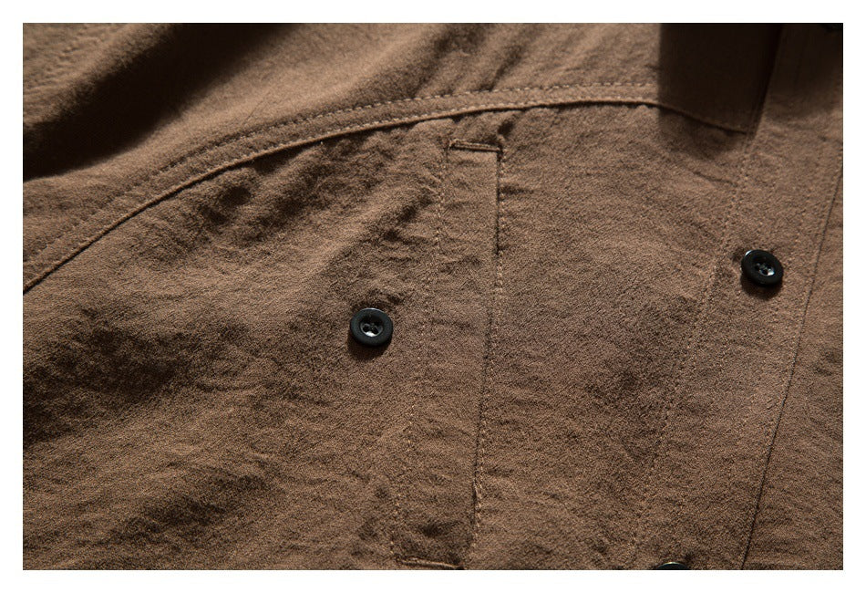 Close-up of the brown shirt's chest pocket with black buttons and visible stitching.