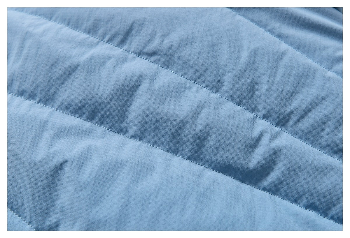 Close-up of light blue jacket fabric with curved stitched panel seams.