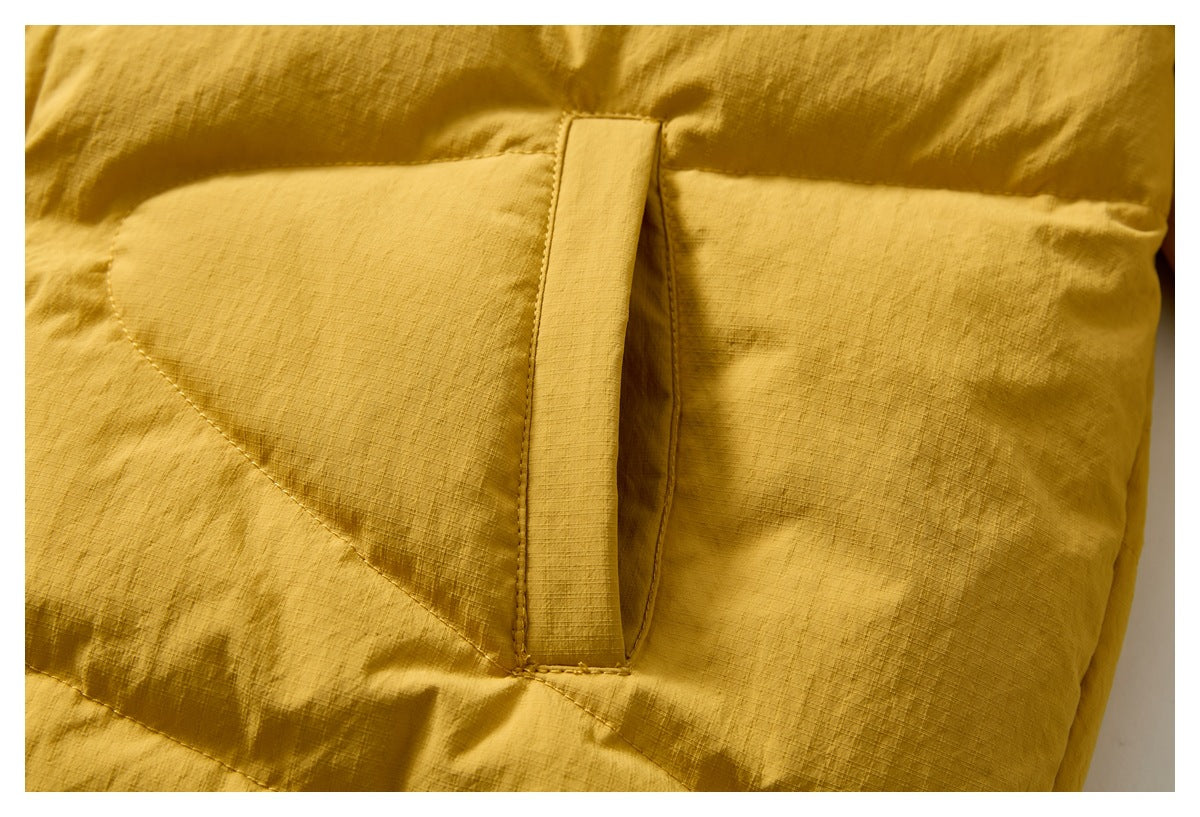 Close-up of a mustard yellow quilted jacket pocket with a vertical fabric tab.