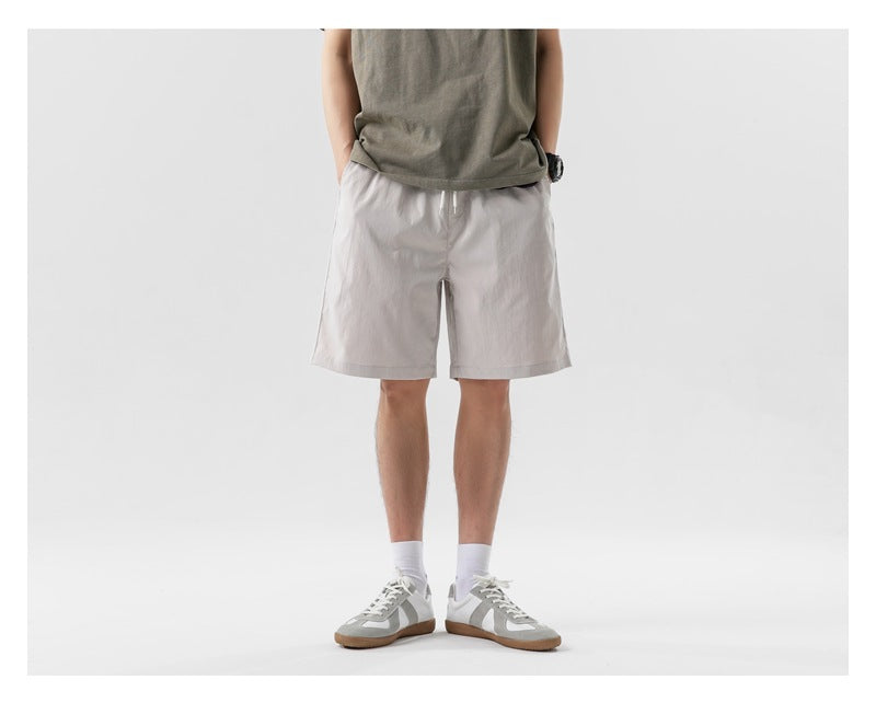Front view of a model wearing light gray drawstring shorts and an olive T-shirt.