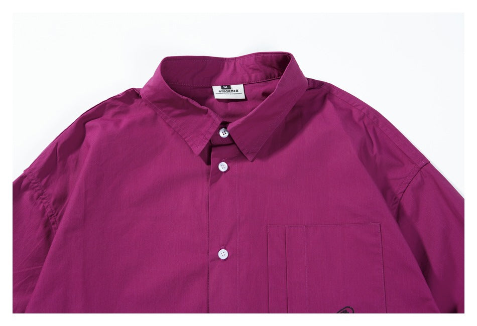 Close view of the magenta shirt's pointed collar, white buttons, chest pocket, and inner neck label.