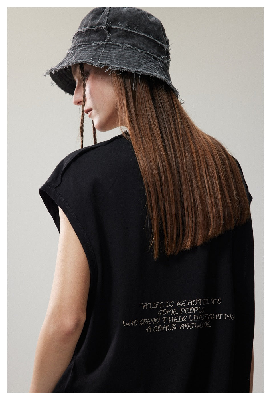 Close-up of the back of a black cap-sleeve T-shirt, showing a handwritten-style English quote print.