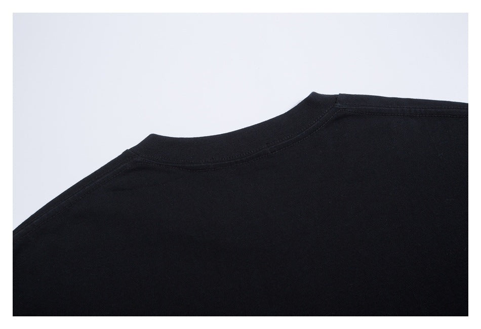 Close-up of a black garment's neckline and shoulder seams against a light background.