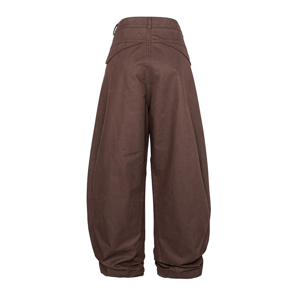 Full rear view of brown wide-leg trousers with curved back pocket flaps and gathered hems.