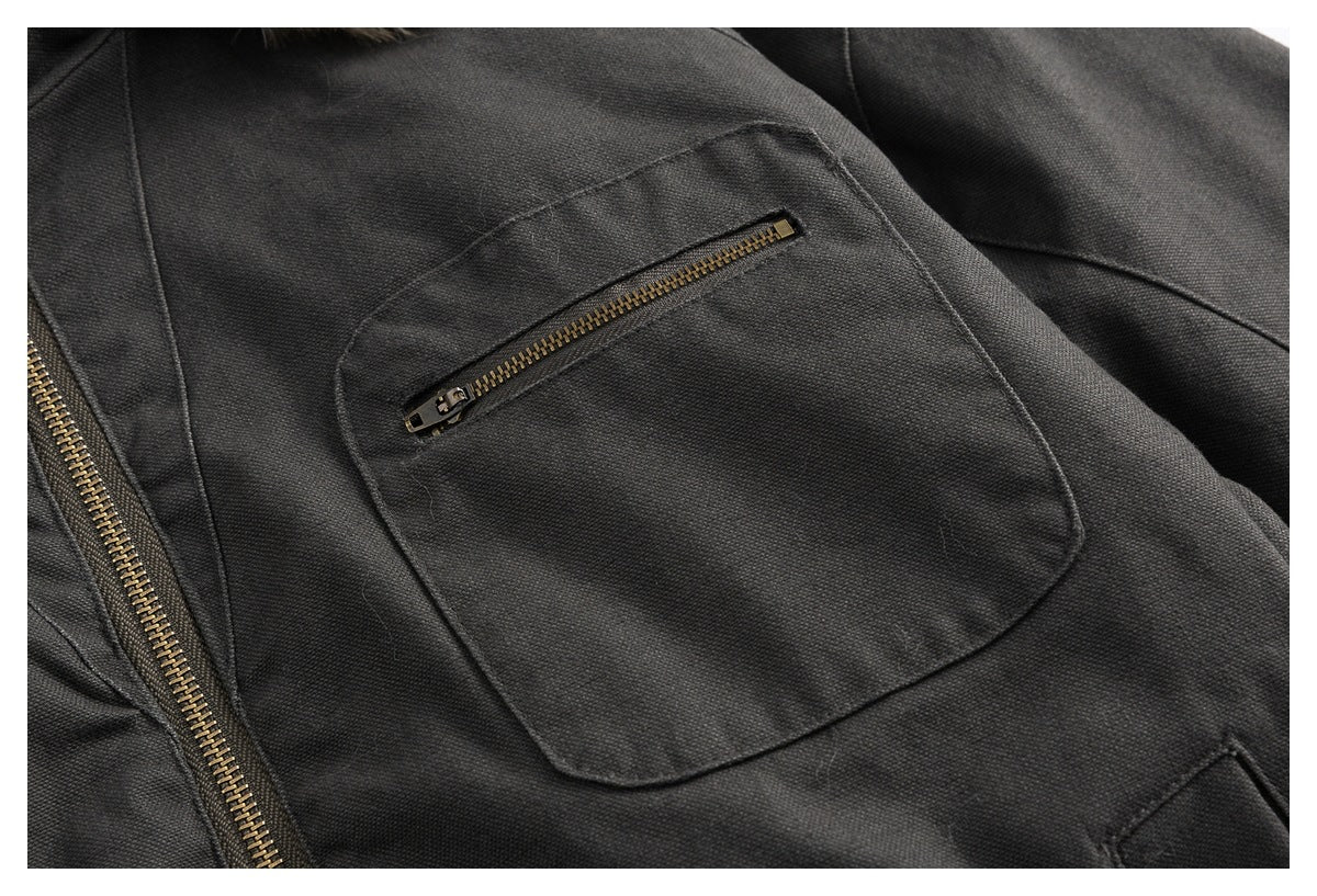 Close-up of a dark jacket's large flap pocket with a short antique-brass zipper.