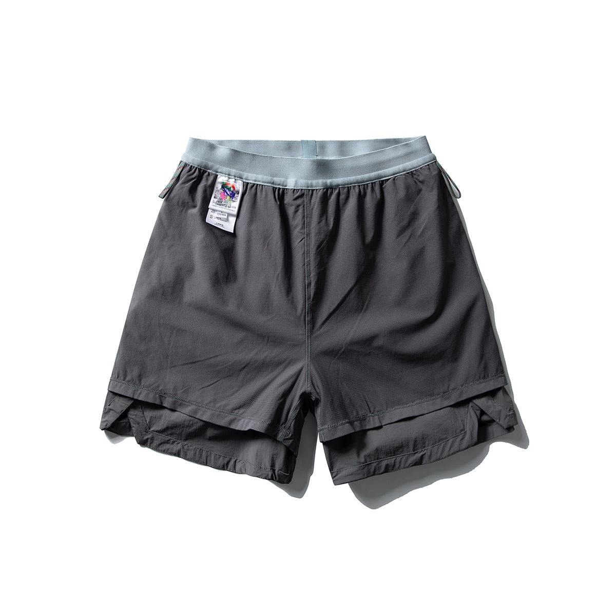 Front view of charcoal layered shorts with a pale blue waistband and an attached hang tag, laid flat on white.