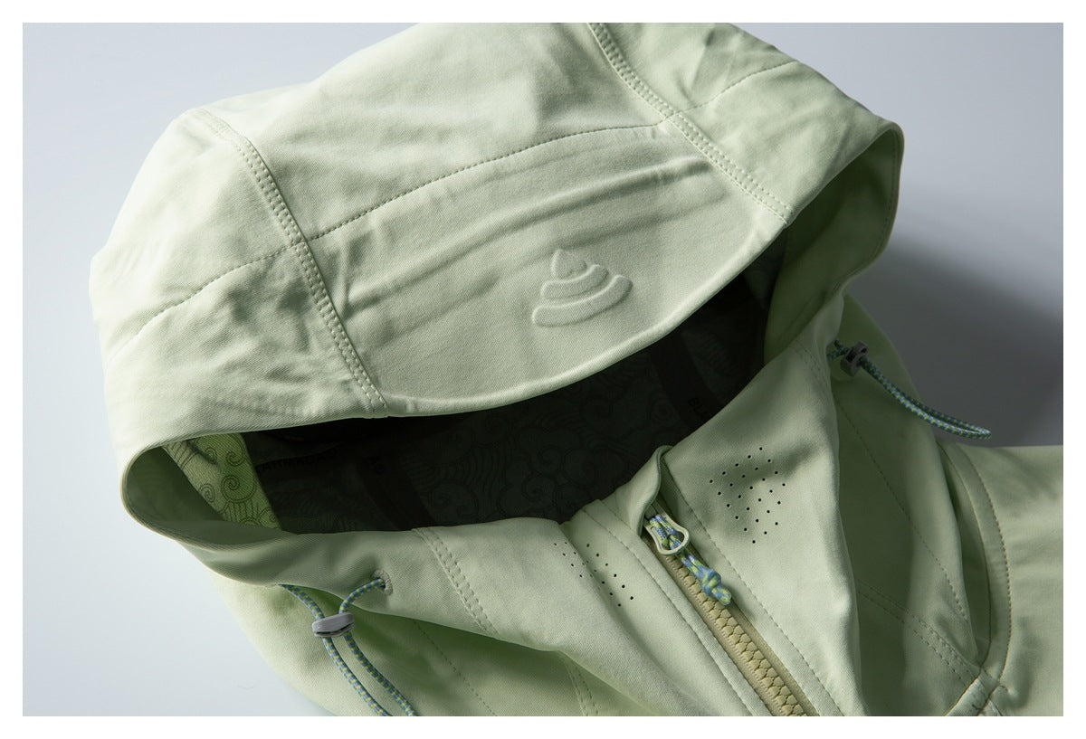 Close-up of a pale green jacket hood, patterned lining, front zipper, and blue-green drawcords.