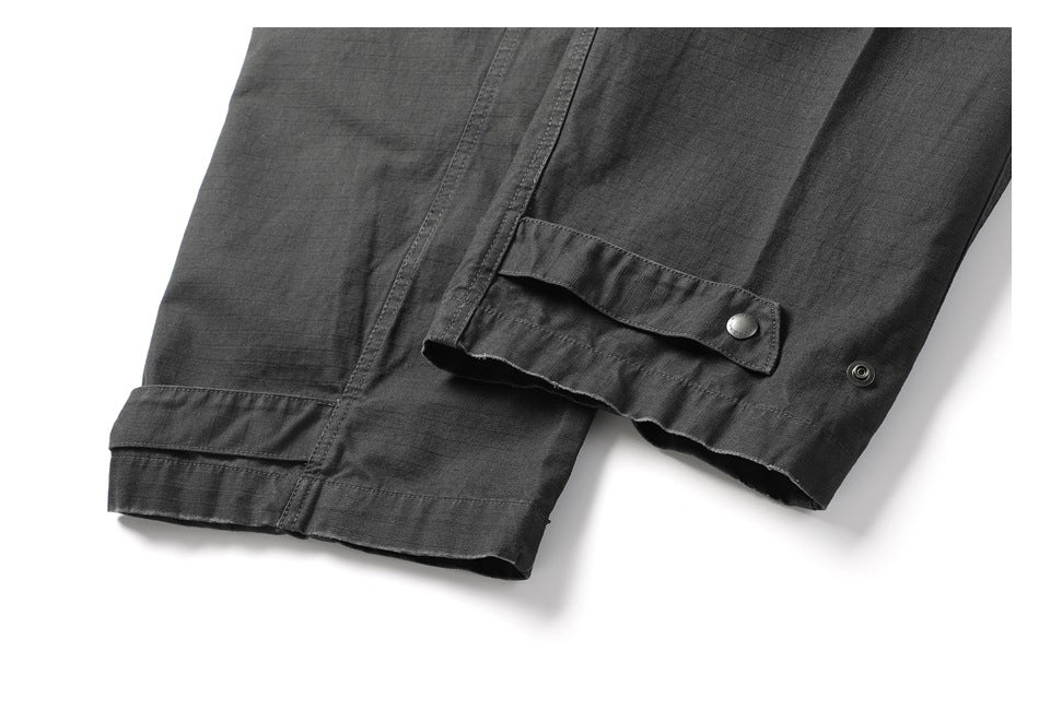 Close-up of charcoal trouser legs and hems, showing a snap-fastened tab detail.