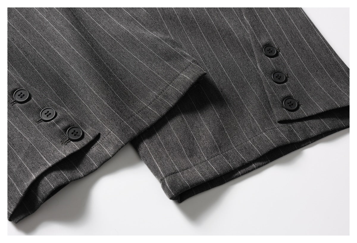 Close-up of charcoal pinstripe garment hem with buttoned tabs along the edge.