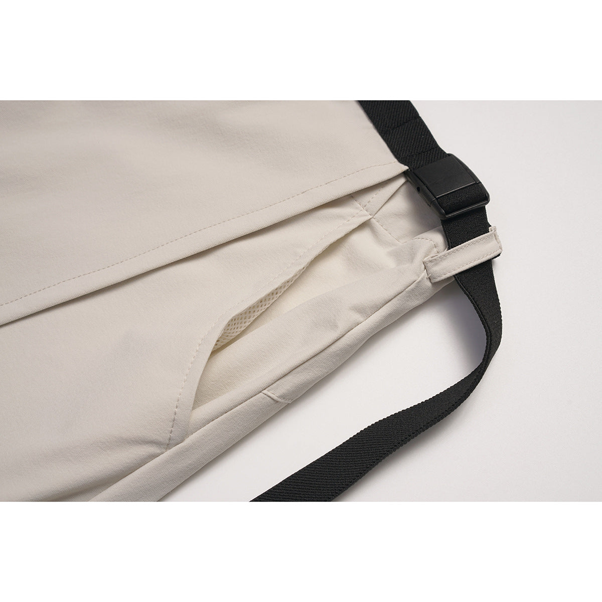 Close-up of the beige skirt's overlapping side panels, inner mesh and adjustable black strap.