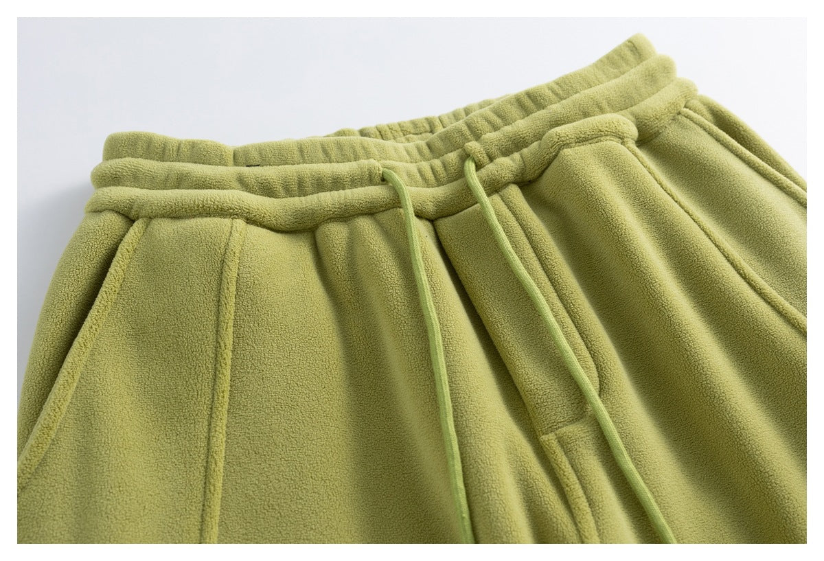 Close-up of olive-green fleece pants showing the elastic waistband, drawstrings and front pocket area.