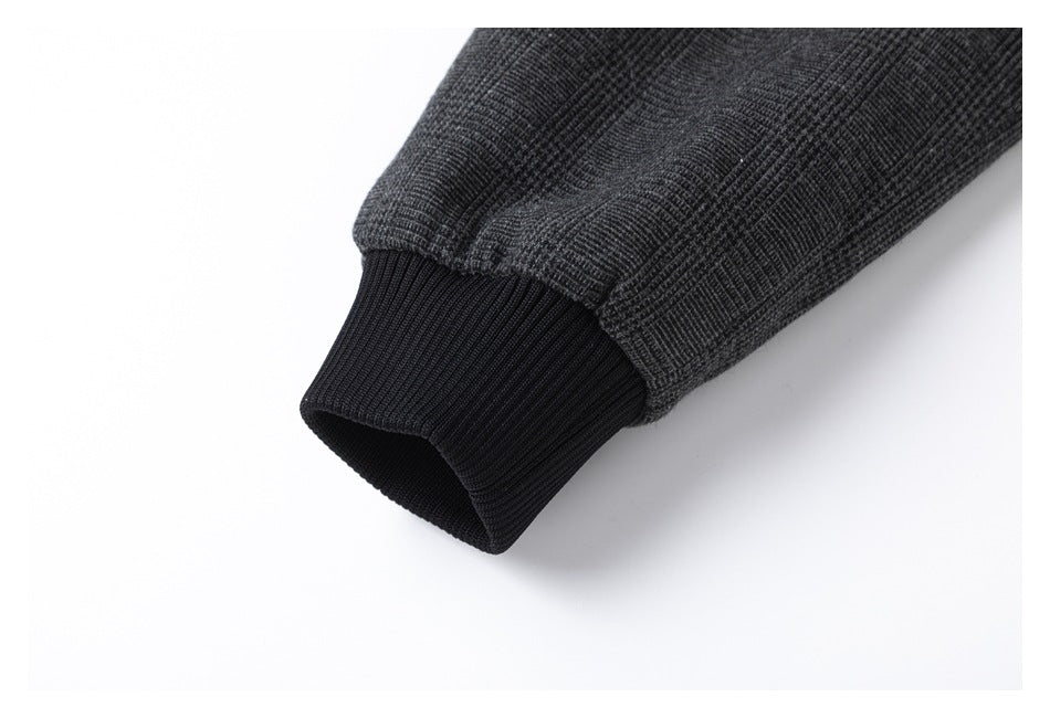 Close-up of a charcoal plaid jacket sleeve ending in a black ribbed cuff.