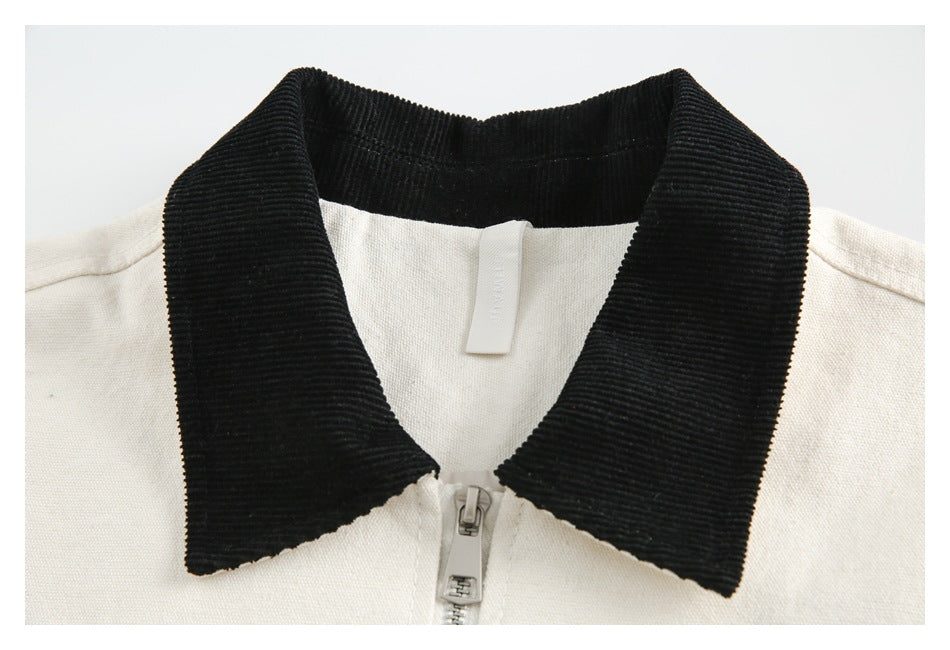 Front collar detail of a cream zip-front garment with a broad black ribbed collar.