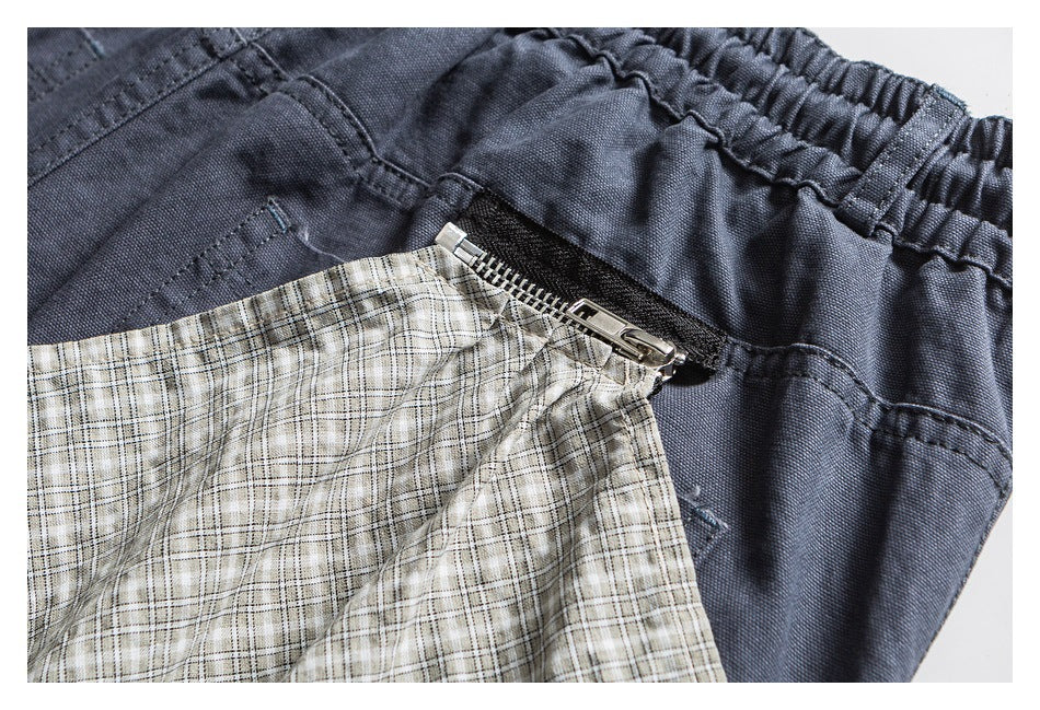 Close-up of dark shorts with a metal zipper pocket and beige plaid lining exposed.