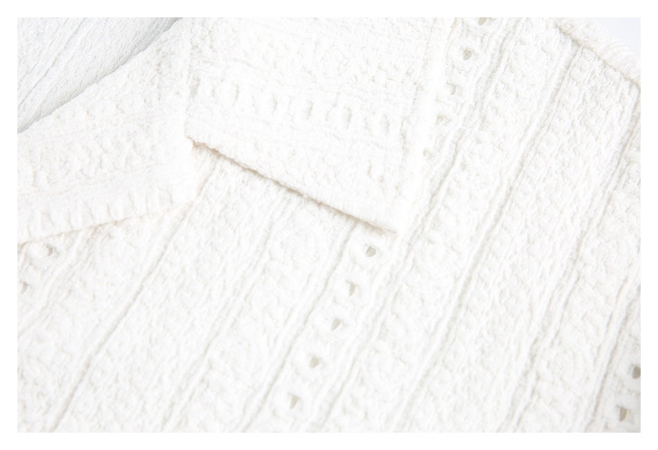 Close-up of a white shirt cuff and textured fabric with rows of openwork stitching.
