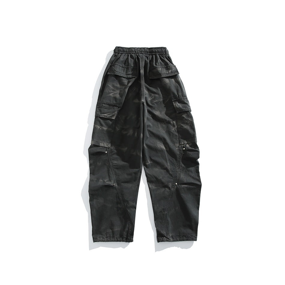 Back view of dark gray tie-dye wash cargo pants with elastic waist, flap pockets and rivet-accented side seams
