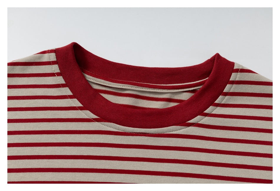Close-up of the shirt's red ribbed crew neckline and red stripes on cream fabric.