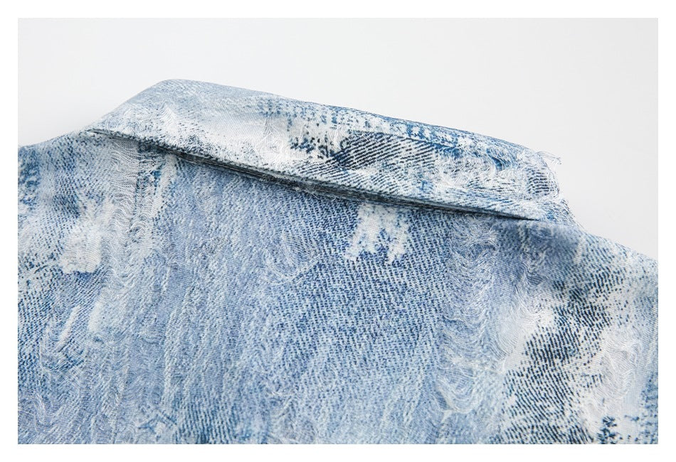 Close-up of a folded garment edge with a stitched seam and pale blue distressed pattern.