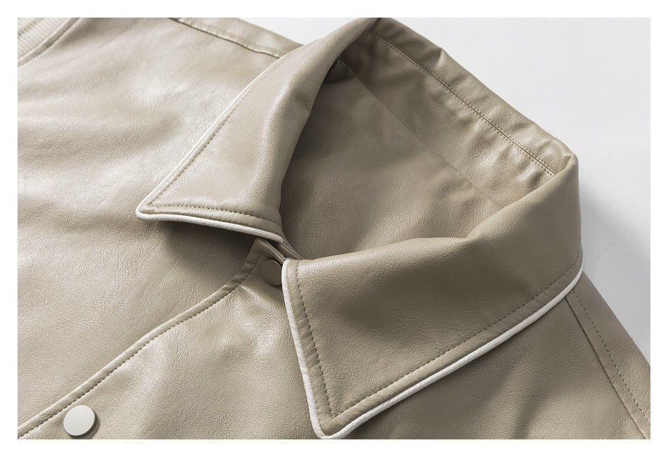 Close-up of a light taupe jacket collar with pale piping and a matching snap button.