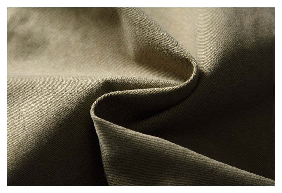 Macro view of khaki trouser fabric folded to show its diagonal weave and texture.
