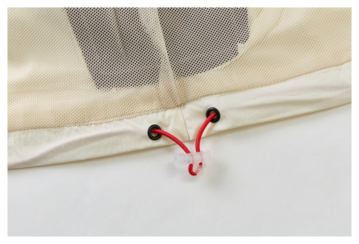Close-up of ivory mesh and hem with black eyelets and a red elastic drawcord toggle.