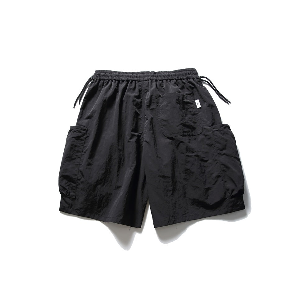 Black shorts with an elastic drawstring waist, patch pockets, and oversized side cargo pockets.