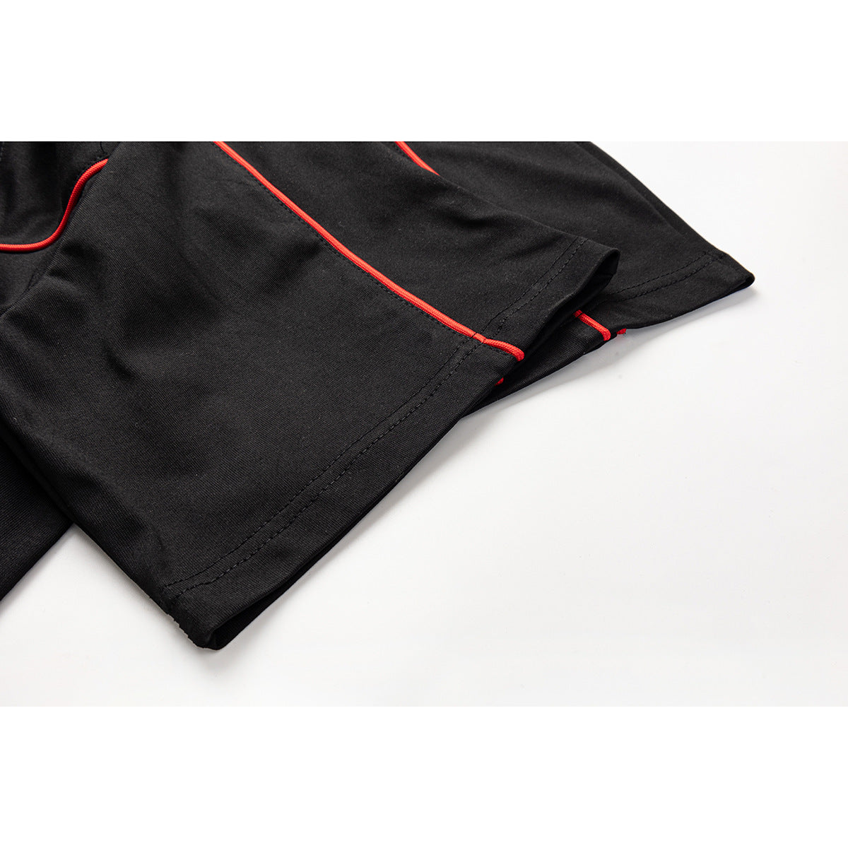 Close-up of a black shirt sleeve hem with red piping and visible stitching.