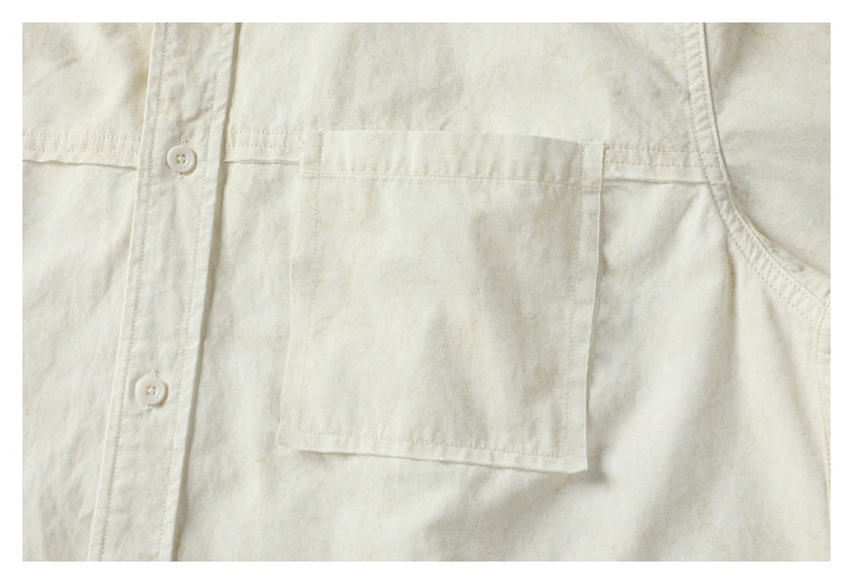 Close-up of the off-white shirt's chest pocket, stitching, and front buttons.