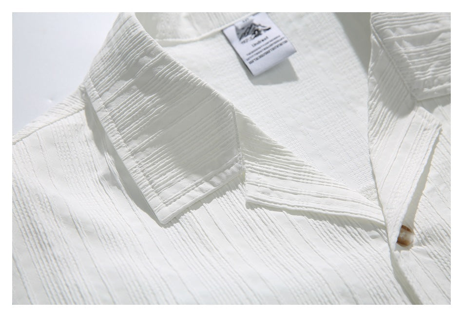 Close-up of a white textured shirt collar and placket, with a small sewn-in neck label.