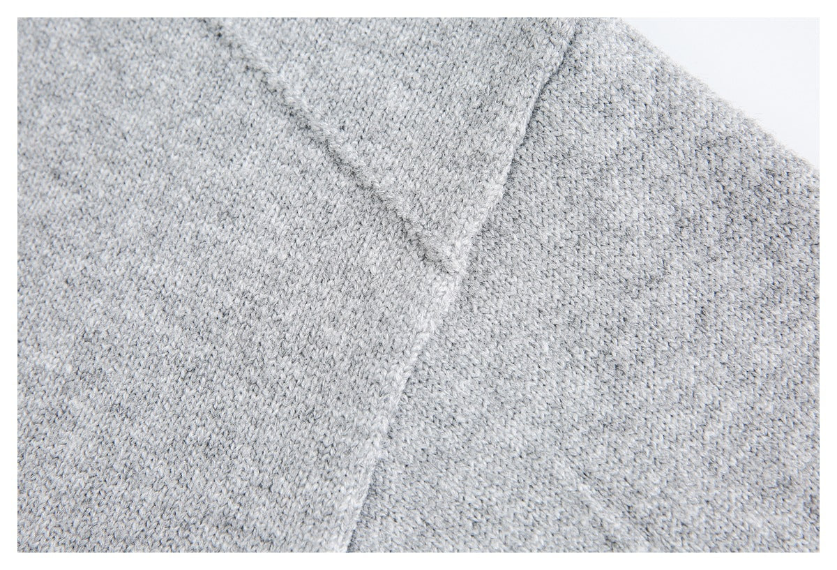 Close-up of light gray knit fabric showing a diagonal seam and textured stitches.