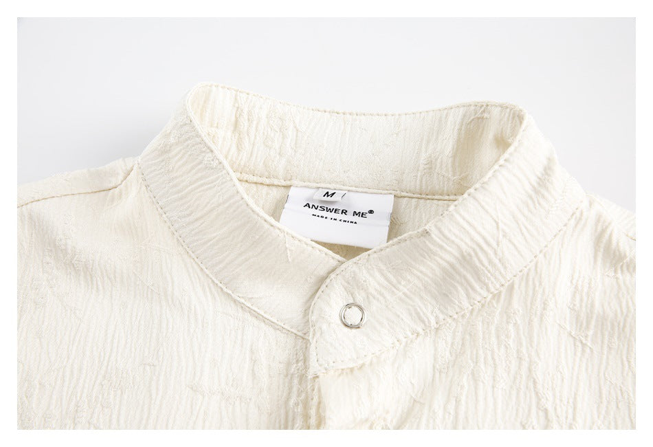 Close-up of an ivory shirt's stand collar, round metal stud, and sewn-in label.