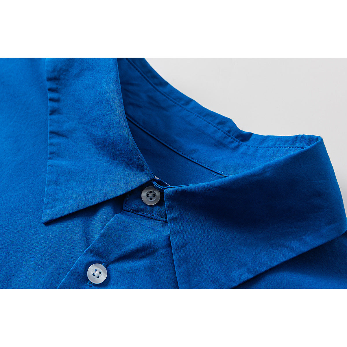 Close-up of a bright blue shirt collar and placket with two pale buttons.