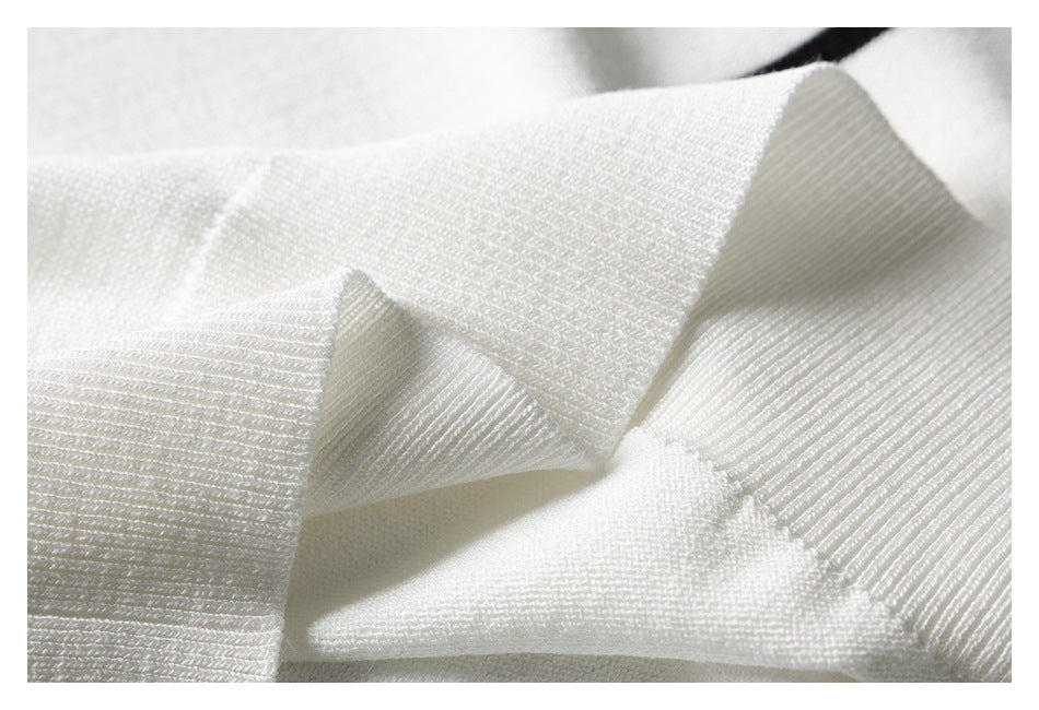 Macro view of white knit sweater fabric and a folded ribbed edge.