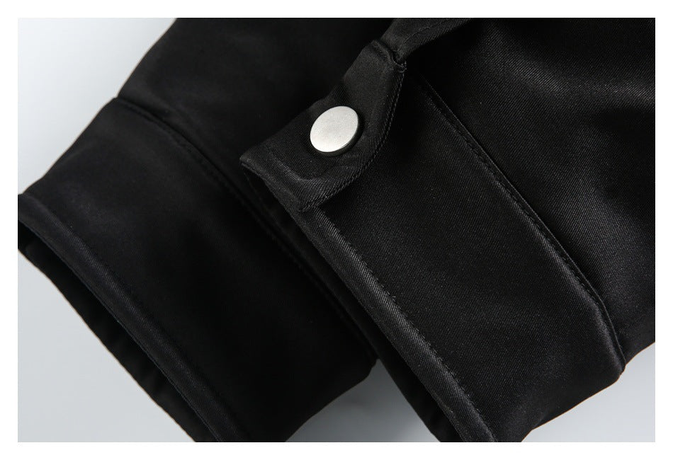 Close-up of a black jacket cuff with a round silver snap on an adjustable tab.