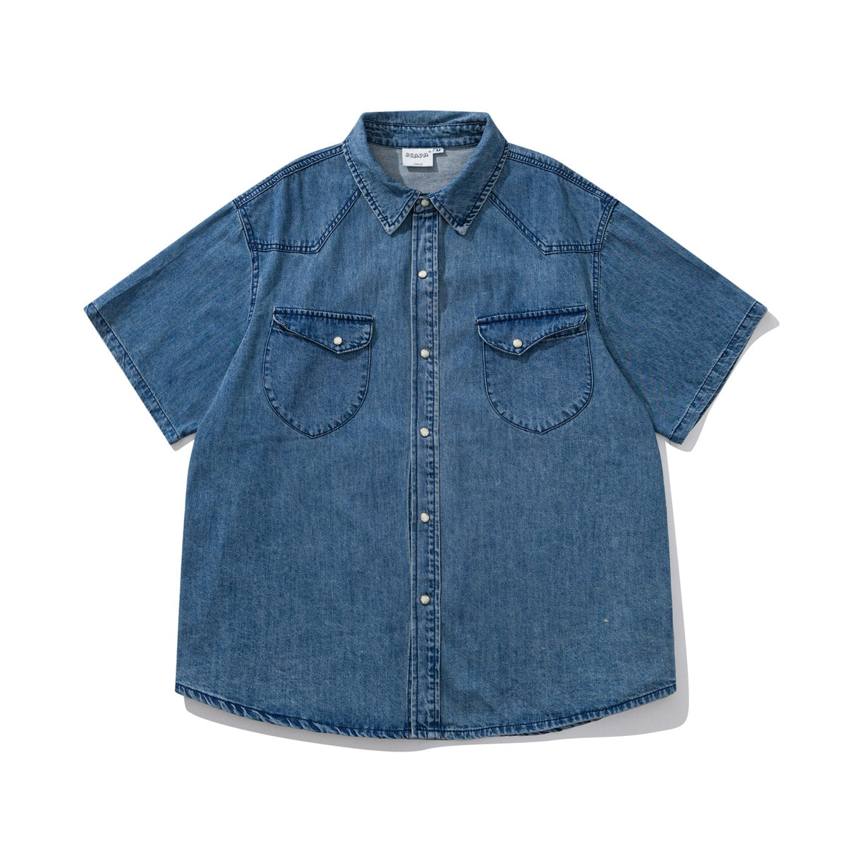 Flat-lay front of a washed blue short-sleeve denim shirt with snap buttons and two flap chest pockets
