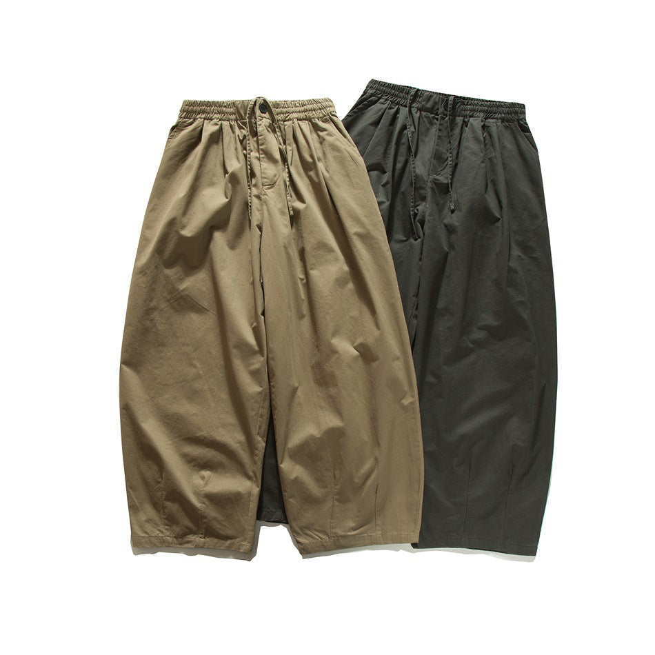 Two pairs of wide-leg trousers shown from the front in khaki and dark charcoal, with elastic waistbands.
