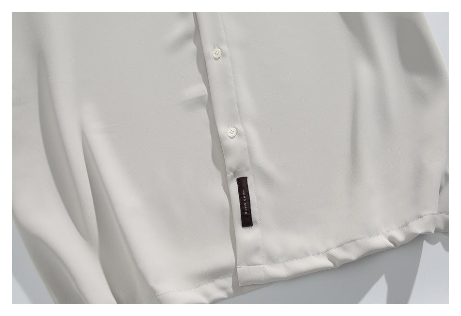 Close-up of the ivory shirt's button placket, lower hem, and small dark sewn label.