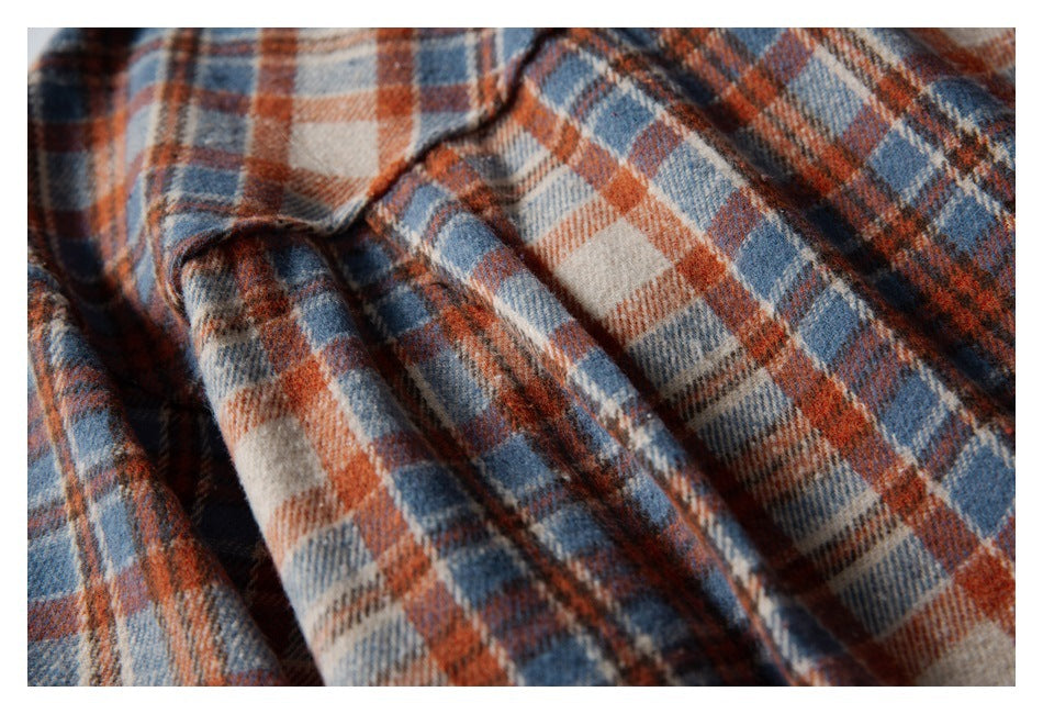 Close-up of soft-looking rust, navy and cream plaid fabric gathered into folds.