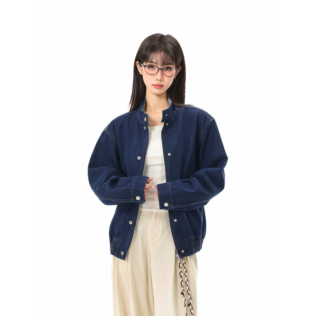 Front view of a model in a dark blue denim jacket with silver snaps, layered over a white top.