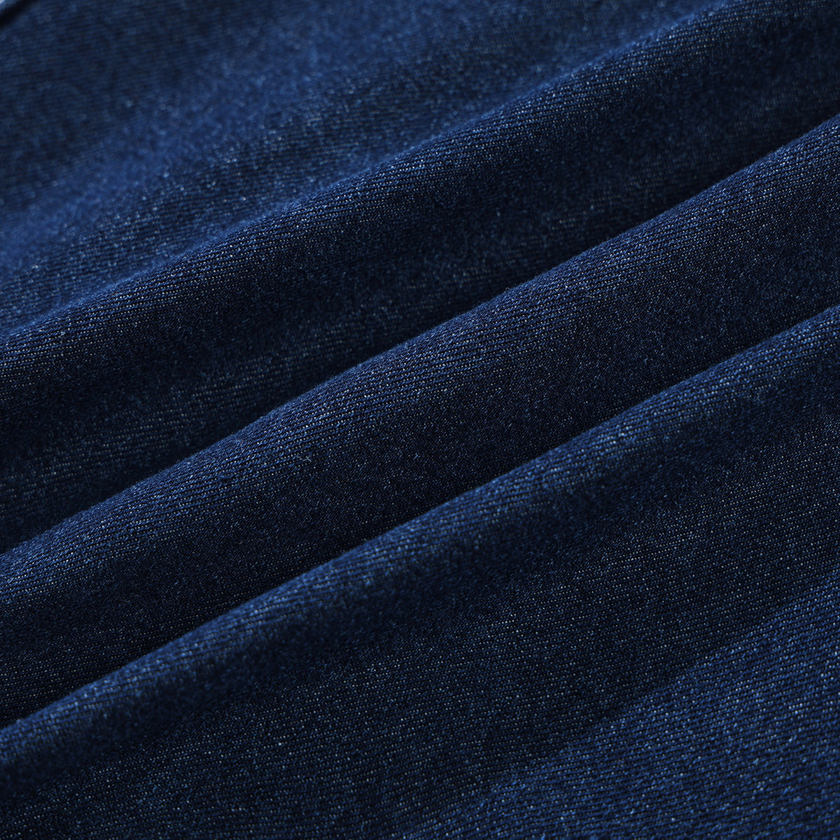 Close-up of dark indigo denim fabric arranged in soft folds.