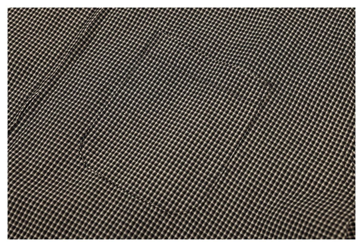 Close-up showing the black and beige small-check pattern and a seam in the garment fabric.